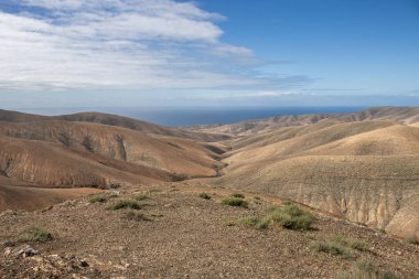 Shapes and lines of the mountains of the volcanic origin. Light brown color of the soil. Sky with clouds in the winter. Mirador Astronomico (Astronimical Viewpoint), Fuerteventura, Canary Islands