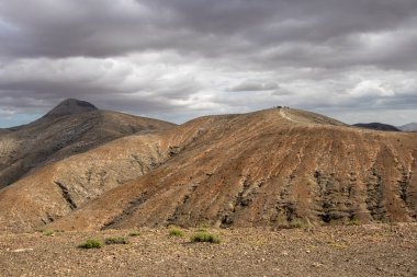 Shapes and lines of the mountains of the volcanic origin. Light brown color of the soil. Sky with clouds in the winter. Mirador Astronomico (Astronimical Viewpoint), Fuerteventura, Canary Islands