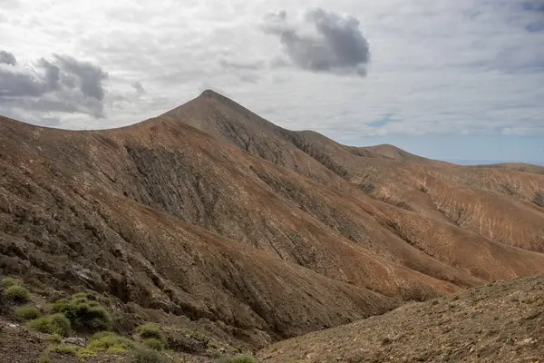 Shapes and lines of the mountains of the volcanic origin. Light brown color of the soil. Sky with clouds in the winter. Mirador Astronomico (Astronimical Viewpoint), Fuerteventura, Canary Islands