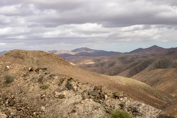 Shapes and lines of the mountains of the volcanic origin. Light brown color of the soil. Sky with clouds in the winter. Mirador Astronomico (Astronimical Viewpoint), Fuerteventura, Canary Islands