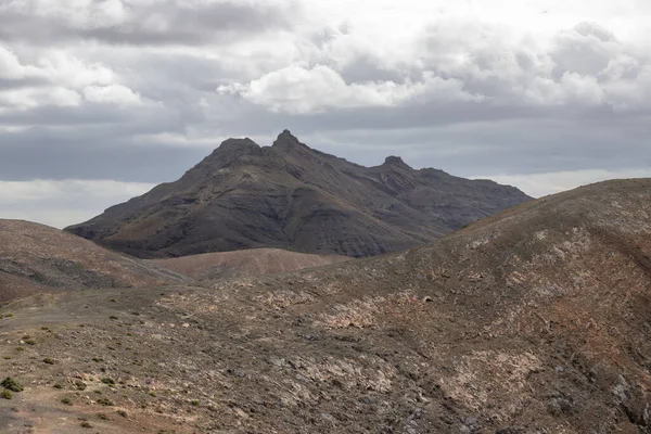 Shapes and lines of the mountains of the volcanic origin. Light brown color of the soil. Sky with clouds in the winter. Mirador Astronomico (Astronimical Viewpoint), Fuerteventura, Canary Islands