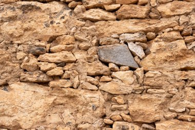 Natural stones mainly of a brown color, creating a wall of a house. Tiscamanita, Fuerteventura, Canary Islands, Spain.