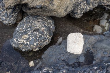 Coast of the Atlantic ocean, with stones and rocks of various shapes. Beauty of the dark grey to black color of them in contrast with white. Playa de las Hermosas, Fuerteventura, Canary Islands, Spain