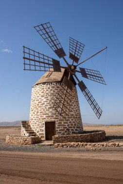 Eski geleneksel yel değirmeni, taştan bir çölde. Kışın beyaz bulutlu mavi gökyüzü. Molino de Tefia, Fuerteventura, Kanarya Adaları, İspanya.