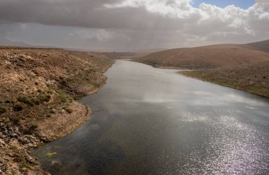 Adalardaki en büyük tatlı su deposu, bir vadide yer almaktadır. En iyi kuş yuvası. Kışın bulutlu bir gökyüzü. Molinos mumyalaması, Fuerteventura, Kanarya Adaları.