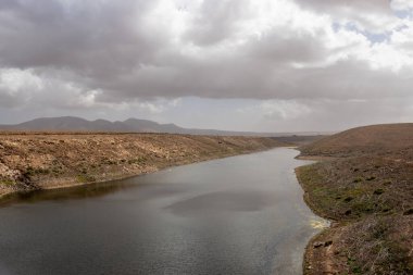 Adalardaki en büyük tatlı su deposu, bir vadide yer almaktadır. En iyi kuş yuvası. Kışın bulutlu bir gökyüzü. Molinos mumyalaması, Fuerteventura, Kanarya Adaları.