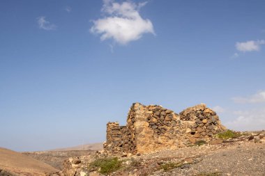 Bir tepenin üzerinde taştan yapılmış küçük bir binanın kalıntıları. Mavi gökyüzü. Molinos Mumyalaması, Fuerteventura, Kanarya Adaları, İspanya