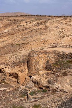 Taşlardan yapılmış küçük yuvarlak bir binanın kalıntıları, bir tepenin içinde, tatlı su deposunu çevreleyen. Molinos Mumyalaması, Fuerteventura, Kanarya Adaları, İspanya