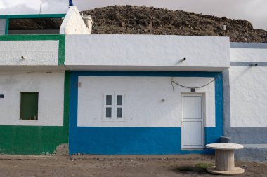 Atlantik Okyanusu kıyısında, kumsalın yanında küçük beyaz evler. Beyaz taban renk detaylarıyla çelişiyor. Los Molinos, Fuerteventura, Kanarya Adaları, İspanya.