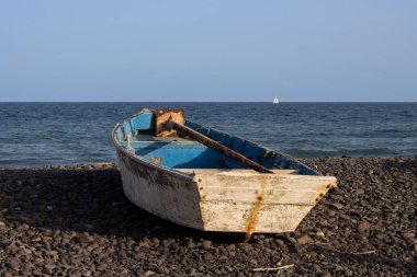 Çakıl taşı sahilinde tahta balıkçı teknesi. Sakin bir Atlantik okyanusu ve mavi bir gökyüzü. Pozo Negro, Fuerteventura, Kanarya Adaları, İspanya.