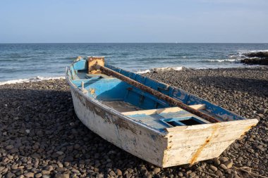 Çakıl taşı sahilinde tahta balıkçı teknesi. Sakin bir Atlantik okyanusu ve mavi bir gökyüzü. Pozo Negro, Fuerteventura, Kanarya Adaları, İspanya.