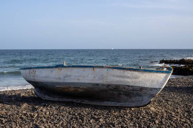Çakıl taşı sahilinde tahta balıkçı teknesi. Sakin bir Atlantik okyanusu ve mavi bir gökyüzü. Pozo Negro, Fuerteventura, Kanarya Adaları, İspanya.