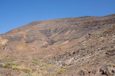 Kışın kuru yüzeyi olan yüksek kayalık dağlar. Parlak mavi gökyüzü. Parkın doğal Jandia, Fuerteventura, Kanarya Adaları, İspanya.