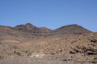Kışın kuru yüzeyi olan yüksek kayalık dağlar. Parlak mavi gökyüzü. Parkın doğal Jandia, Fuerteventura, Kanarya Adaları, İspanya.