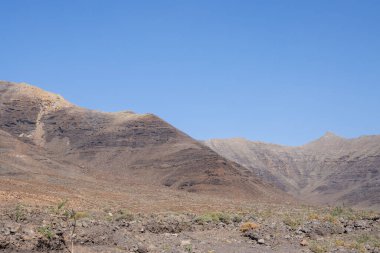 Atlantik Okyanusu 'nun batı-güney kıyılarını çevreleyen yüksek dağlar. Kışın açık mavi gökyüzü. Gran Valle do Cofete, Fuerteventura, Kanarya Adaları, İspanya.