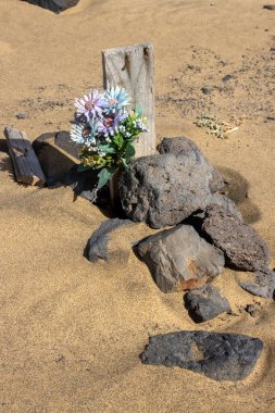 Kimseye ve herkese ait olmayan Atlantik Okyanusu sahilinde yerel sakinler için bir mezarlık inşa edildi. Kumsalın kumları arasında haçlar ve mezar taşları. Kahve, Fuerteventura.