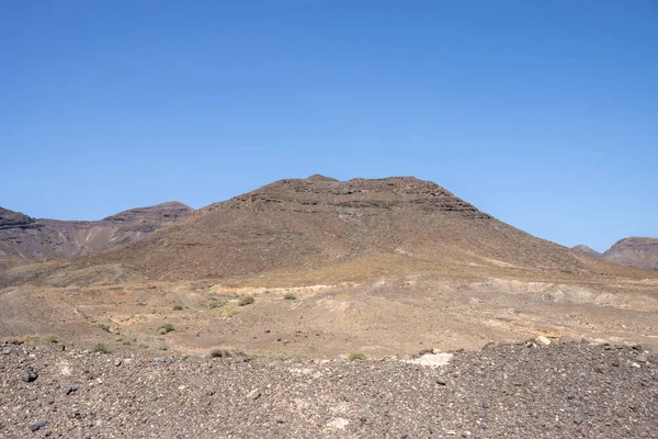 High rocky mountains with a dry surface in the winter.  Bright blue sky. Parque natural Jandia, Fuerteventura, Canary Islands, Spain.