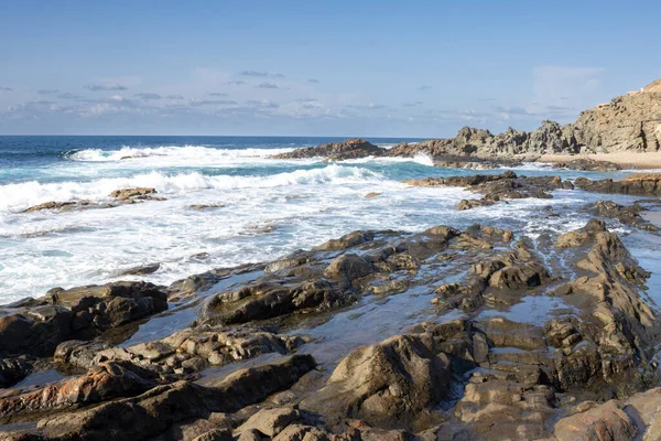 Adanın batısındaki Atlantik Okyanusu plajı. Koyu kahverengiden siyah kayalara doğal havuzlar oluşturur. Kışın güneşli bir gün. Aguas Verdes, Fuerteventura, Kanarya Adaları, İspanya.
