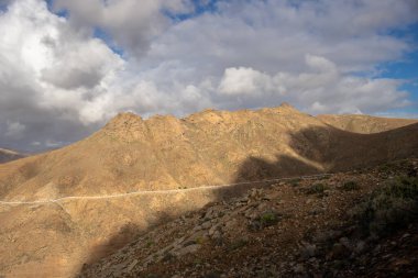 Adanın merkezindeki yüksek dağlar, küçük bir yol hattıyla. Yoğun bulutlar. Mirador del Risco de las Penas, Betancuria, Fuerteventura, Kanarya Adaları, İspanya.