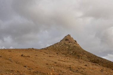 Adanın merkezindeki yüksek dağlar. Bir tanesini bulutlu gökyüzünün altında gördüm. Kuru toprak. Mirador las Penitas, Betancuria, Fuerteventura, Kanarya Adaları, İspanya.