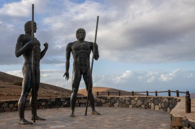 Guise ve Ayose heykelleri, ada tarihinin iki kralı. Kışın bulutlu bir gökyüzü. Mirador de Morro Velosa, Betancuria, Fuerteventura, İspanya.