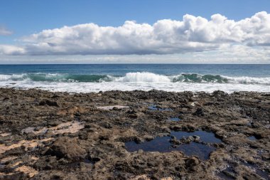 Başkentteki Atlantik Okyanusu 'nun Rocky sahili. Kışın beyaz bulutlu mavi gökyüzü. Puerto del Rosario, Fuerteventura, İspanya.