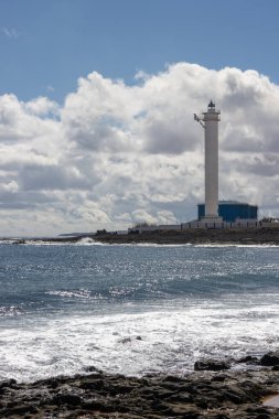 Atlantik Okyanusu kıyılarında kıyı şeridinde ışık dalgaları var. Beyaz bir deniz feneri olan sanayi bölgesinin manzarası. Başkent Puerto del Rosario, Fuerteventura, İspanya.