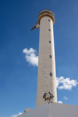 Başkentin sanayi bölgesinde bir deniz feneri. Uzun beyaz bir bina. Beyaz bulutlu parlak mavi gökyüzü. Puerto del Rosario, Fuerteventura, İspanya.