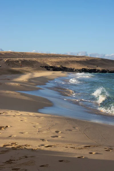 Sandy beach of the Atlantic ocean, no people in the winter season. Bright blue sky. Turquoise water. Parque natural Dunas de Corralejo, Fuerteventura, Spain.