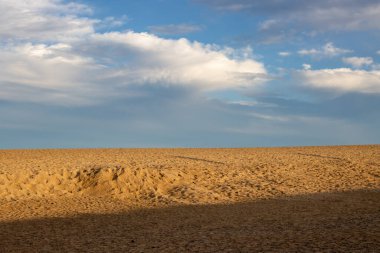 Doğal parktaki kum tepeleri, altın saat boyunca renkliydi. Genişliğinde bulutlar olan mavi gökyüzü. Park Natural de Dunas de Corralejo, Fuerteventura, İspanya.