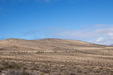 Adanın güneyinde, tepeleri ve ıssız toprakları olan bir yer. Beyaz bulutlu mavi gökyüzü. Costa Calma, Fuerteventura, Kanarya Adaları, İspanya.