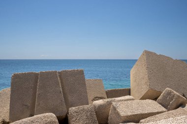 Betondan yapılmış devasa kübik nesneler, yerel marinada deniz kenarı olarak kullanılıyor. Akdeniz 'in sakin suları (Tyrhenian). Baharın başlarında mavi gökyüzü. Marsala, Batı Sicilya, İtalya.