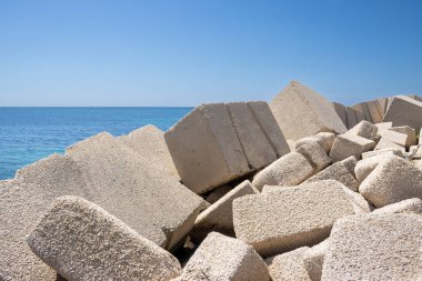 Betondan yapılmış devasa kübik nesneler, yerel marinada deniz kenarı olarak kullanılıyor. Akdeniz 'in sakin suları (Tyrhenian). Baharın başlarında mavi gökyüzü. Marsala, Batı Sicilya, İtalya.