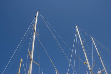 Denizcilere parkedilmiş yatların direkleri ve diğer ekipmanlarına bakın, soyut bir resim oluşturun. Parlak mavi gökyüzü. Marsala, Sicilya, İtalya.