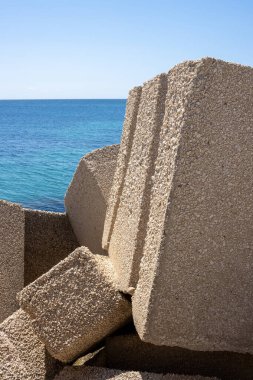 Betondan yapılmış devasa kübik nesneler, yerel marinada deniz kenarı olarak kullanılıyor. Akdeniz 'in sakin suları (Tyrhenian). Baharın başlarında mavi gökyüzü. Marsala, Batı Sicilya, İtalya.