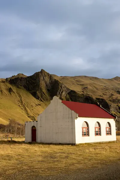 典型的北欧建筑 在一座大山下有红色屋顶的白色房子 青草和苔藓的黄绿色 秋天多云的天空 大西洋岛屿南部冰岛 — 图库照片