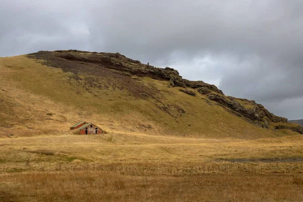 牧草地に小さな伝統的な元の家は 山の下 秋には草の黄色 曇った空 アイスランド南中部 — ストック写真