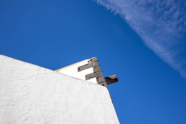 Deetails of the traditional spanish architecture with a white facade. Bright blue sky with contrast white chemtrails. Teguise, Lanzarote, Canary Islands, Spain.