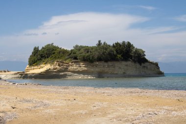 Adanın kuzey kesimindeki İyon (Akdeniz) kıyısında doğal kaya oluşumları. Denizin sakin suları. Baharda açık bulutlu mavi gökyüzü. Sidari, Korfu, Yunanistan.