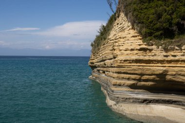 Adanın kuzey kesimindeki İyon (Akdeniz) kıyısında doğal kaya oluşumları. Denizin sakin suları. Baharda açık bulutlu mavi gökyüzü. Sidari, Korfu, Yunanistan.