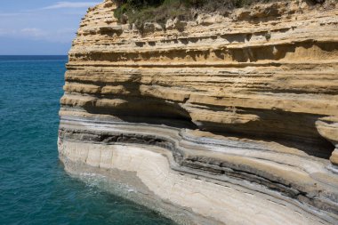 Adanın kuzey kesimindeki İyon (Akdeniz) kıyısında doğal kaya oluşumları. Denizin sakin suları. Baharda açık bulutlu mavi gökyüzü. Sidari, Korfu, Yunanistan.