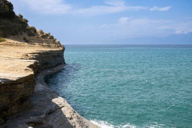 Adanın kuzey kesimindeki İyon (Akdeniz) kıyısında doğal kaya oluşumları. Denizin sakin suları. Baharda açık bulutlu mavi gökyüzü. Sidari, Korfu, Yunanistan.