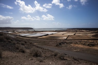Janubio Saline 'deki küçük göletlerin geometrik deseni, tuz üretimi. Atlantik Okyanusu 'nun Ufku. Hafif bulutlar. Salinas de Janubio, Lanzarote, Kanarya Adaları, İspanya.