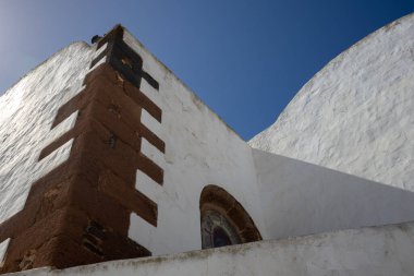 Adadaki geleneksel mimarinin zararları. Turuncu-kahverengi kiremitli binanın beyaz cephesi. Parlak mavi gökyüzü. Teguise, Lanzarote, Kanarya Adaları, İspanya.