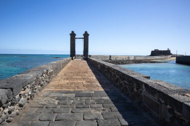 Atlas Okyanusu 'nda, Aziz Gabriel Kalesi' ne (Castillo de San Gabriel) giden bir köprü. Okyanusun sakin suları ve ufku. Kale arka planda. Arrecife, Lanzarote, Kanarya Adaları, İspanya.