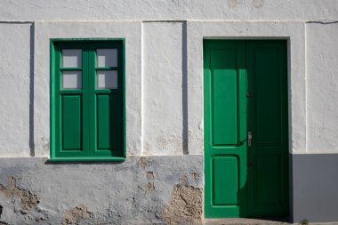 Beyaz binalı bir cadde, tüm ada için tipik. Kapıların ve pencerelerin geleneksel İspanyol yeşili rengi. Parlak güneş ışığı. Arrecife, Lanzarote, Kanarya Adaları, İspanya.
