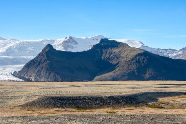 Avrupa 'nın en büyük buzulunun etrafındaki sonbahar ülkesi. Dağlar ve tarlalar buzulun güzelliğinin altını çiziyor. Vatnajokull, Güneydoğu İzlanda.