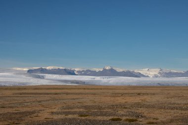 Avrupa 'nın en büyük buzulunun etrafındaki sonbahar ülkesi. Dağlar ve tarlalar buzulun güzelliğinin altını çiziyor. Vatnajokull, Güneydoğu İzlanda.