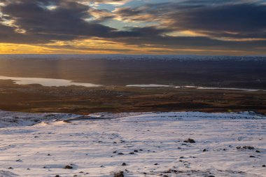 Gün batımında nehri olan karlı bir ülkedeki bir dağdan manzara. Seydisfjordur, Doğu İzlanda.