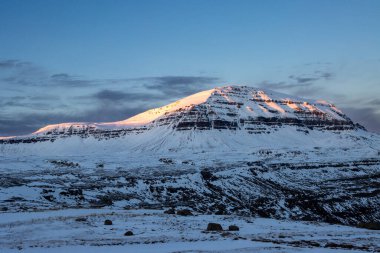 Sonbaharda karla kaplı dağların görkemli güzelliği. Gün batımının erken saatlerinde gökyüzüne dokunan renkler. Seydisfjorur, Doğu İzlanda